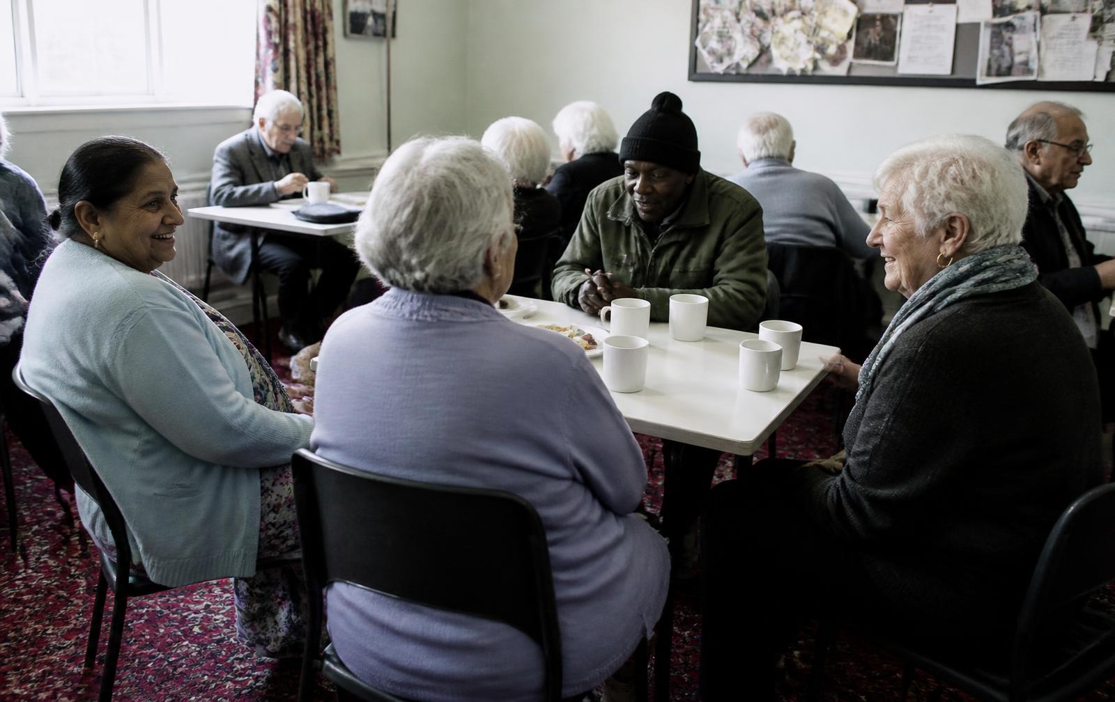 Older people sitting together with cups of tea at a community centre afternoon